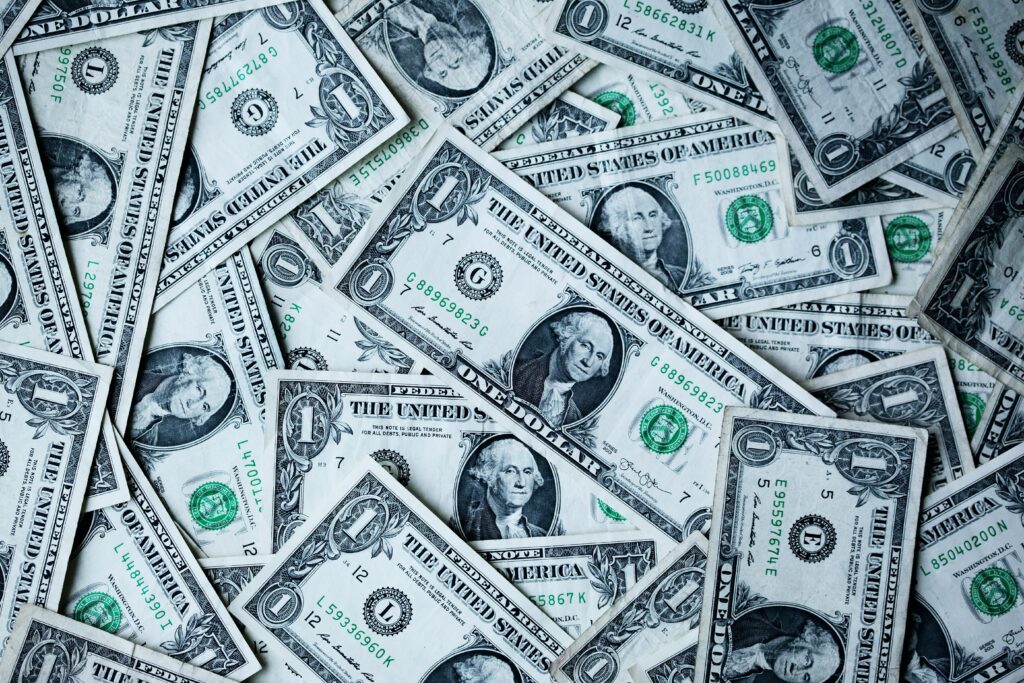 Nom : dépenses publiques en augmentation aux USA / Description : tapis de billets de 1 $ éparpillés, symbole d'une gestion discutable